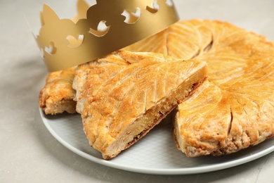 Photo of Traditional galette des Rois with paper crown on light grey marble table