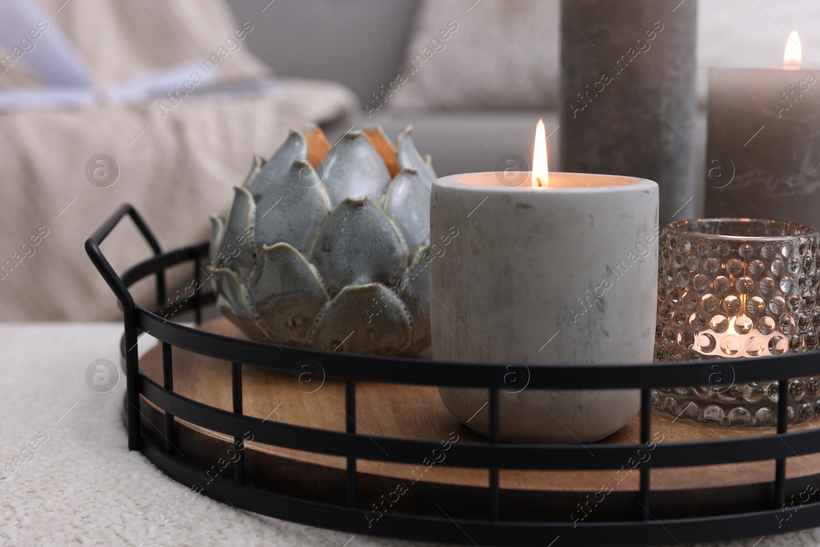 Photo of Tray with burning candles on ottoman indoors