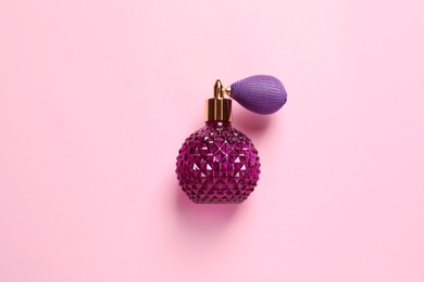 Bottle of perfume on pink background, top view