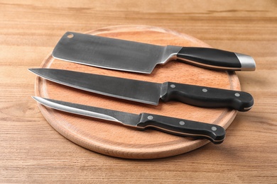 Photo of Board with set of knives on wooden background