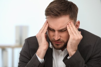 Photo of Young man suffering from migraine indoors, closeup