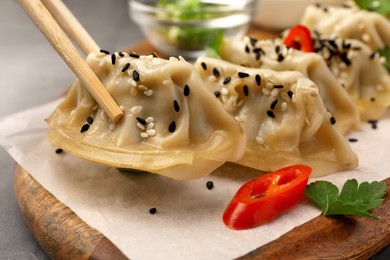 Photo of Taking delicious gyoza (asian dumpling) from board at table, closeup
