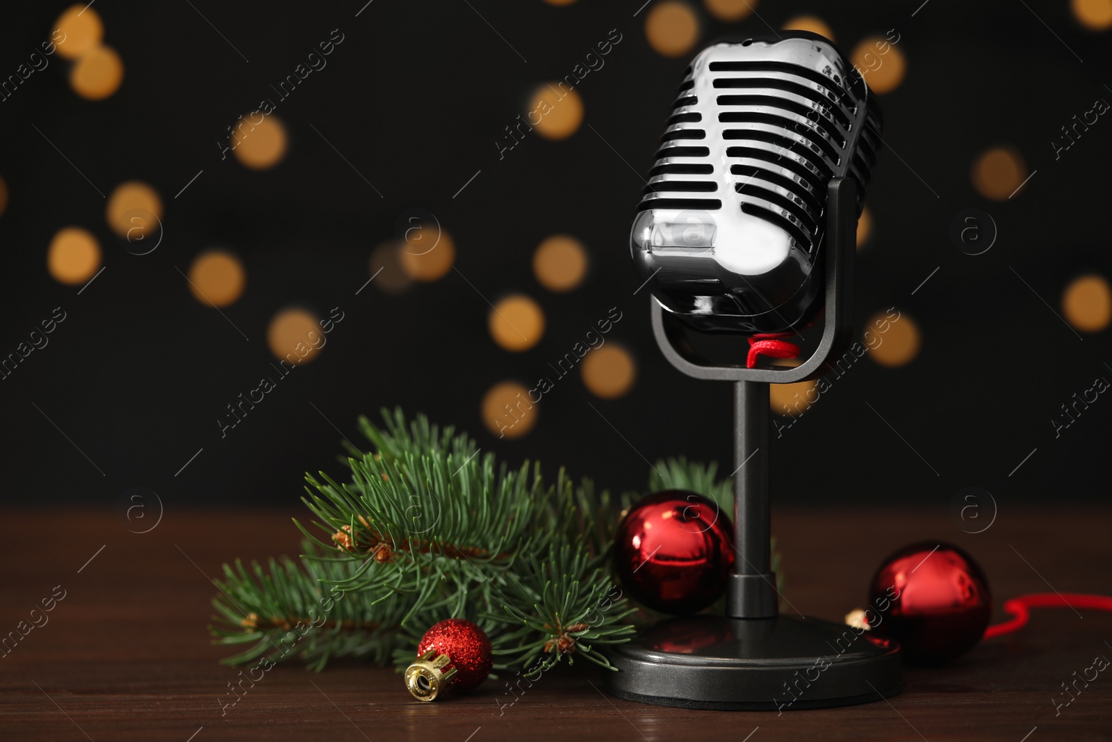 Photo of Retro microphone and festive decor on wooden table against blurred lights, space for text. Christmas music