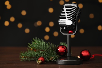 Retro microphone and festive decor on wooden table against blurred lights, space for text. Christmas music