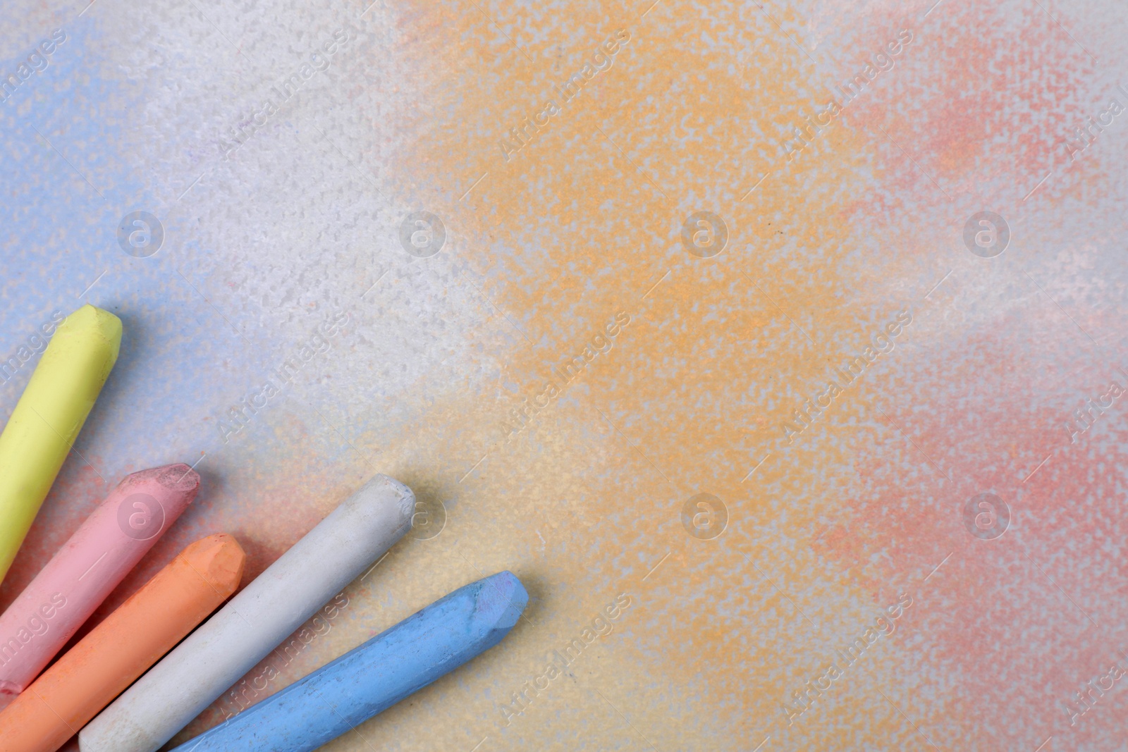 Photo of Colorful pastel chalks on abstract drawing, flat lay. Space for text