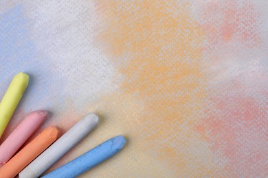 Colorful pastel chalks on abstract drawing, flat lay. Space for text