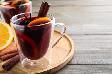 Photo of Aromatic mulled wine on wooden table, closeup. Space for text