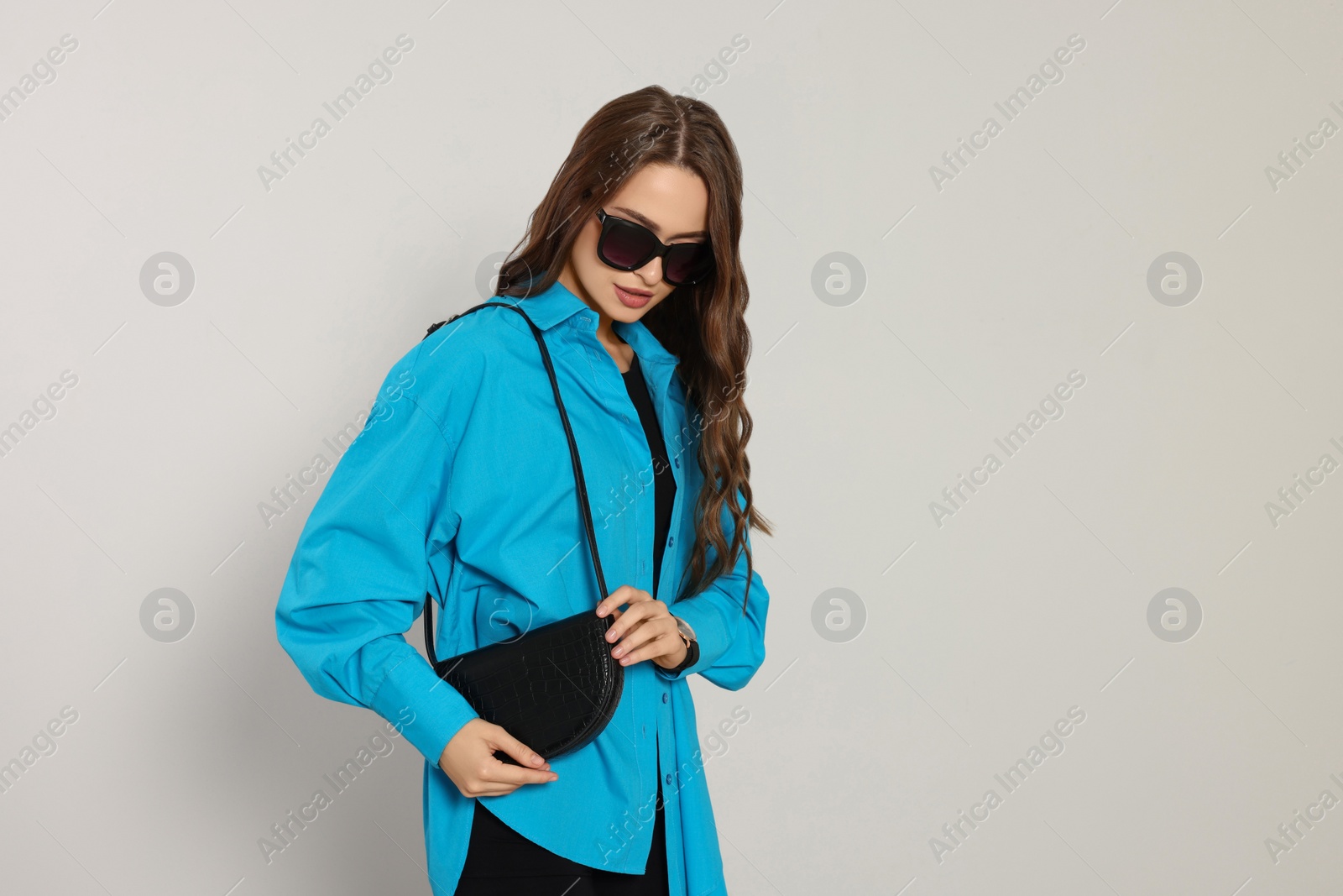 Photo of Beautiful young woman in fashionable outfit with stylish bag on white background, space for text