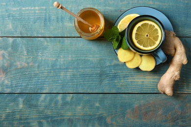 Composition with cup of lemon tea, honey and ginger on wooden background, top view. Space for text