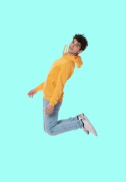 Image of Teenage boy jumping on light blue background, full length portrait