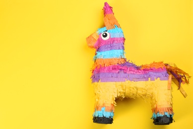 Bright donkey pinata on yellow background, top view. Space for text