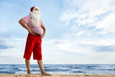 Photo of Santa Claus on beach, space for text. Christmas vacation