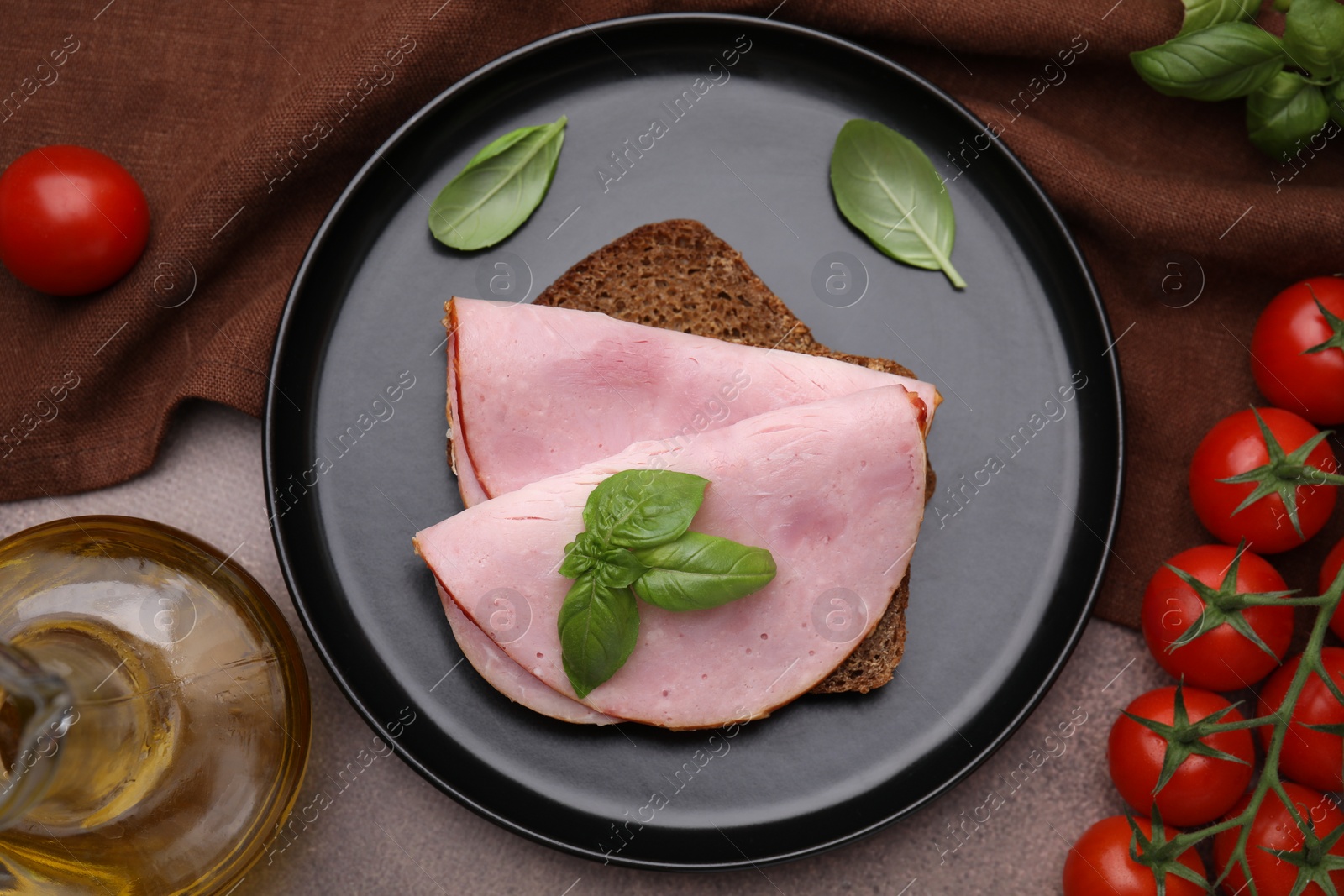 Photo of Delicious sandwich with ham, tomatoes and oil on brown table, flat lay