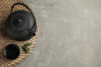 Photo of Cup and teapot of hot aromatic beverage on grey table, flat lay. Space for text