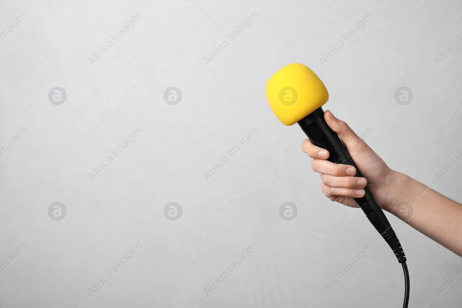 Photo of Woman holding microphone on color background, space for text