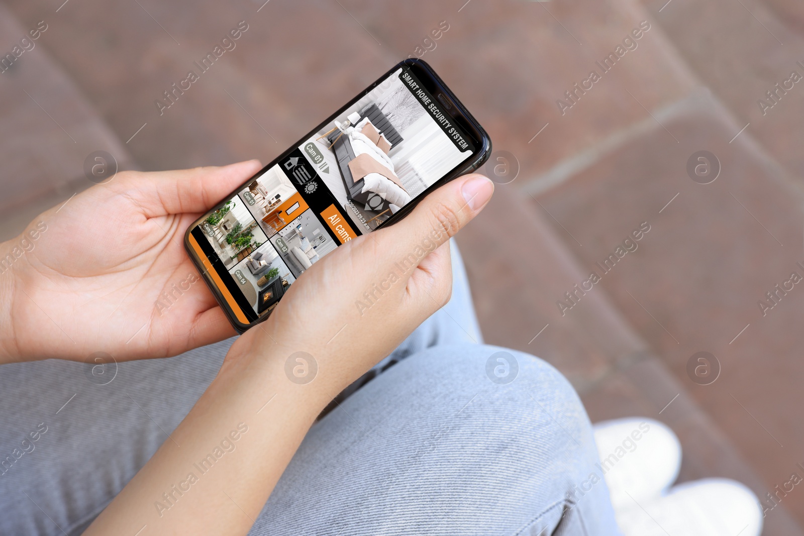 Image of Woman using smart home security system on mobile phone outdoors, closeup. Device showing different rooms through cameras