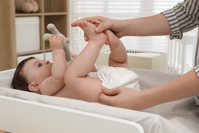 Mother changing baby's diaper on table at home, closeup