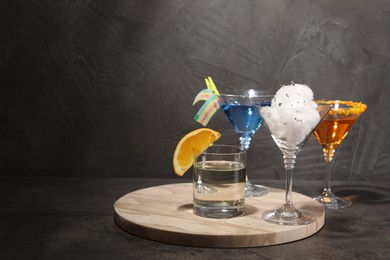 Photo of Tasty cotton candy cocktail and other alcoholic drinks in glasses on gray textured table, space for text