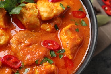 Photo of Bowl of delicious chicken curry on table, closeup