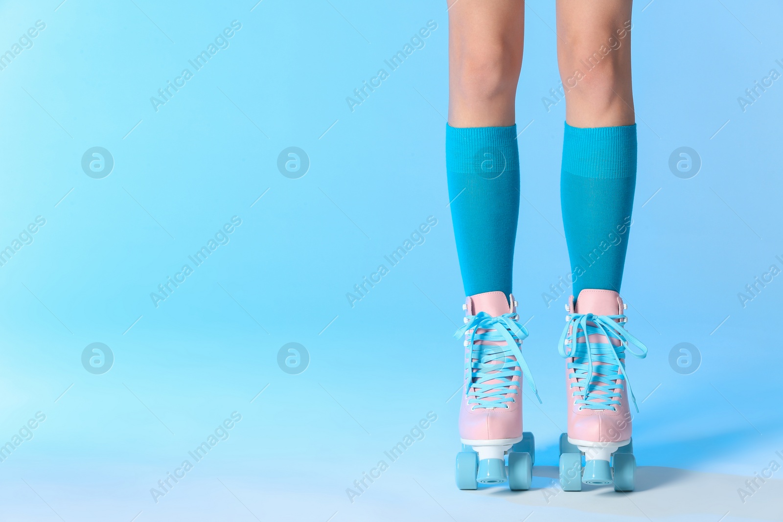 Photo of Woman with vintage roller skates on color background, closeup. Space for text