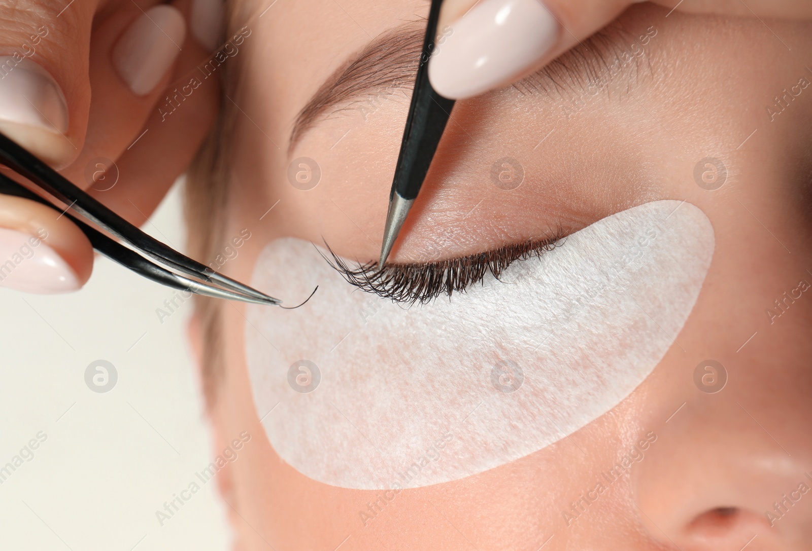 Photo of Young woman undergoing eyelash extension procedure, closeup