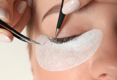 Photo of Young woman undergoing eyelash extension procedure, closeup