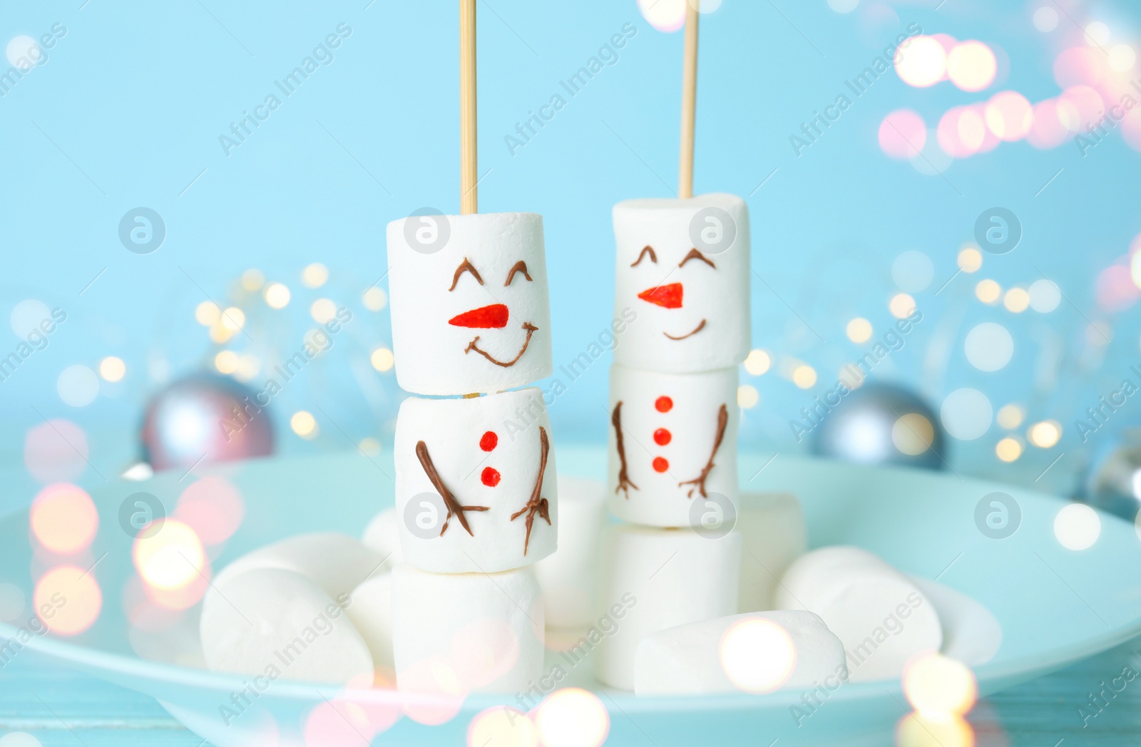 Image of Funny snowmen made of marshmallows in plate, closeup. Bokeh effect 