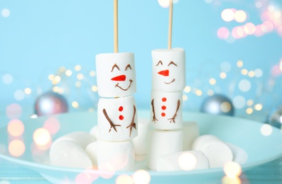 Image of Funny snowmen made of marshmallows in plate, closeup. Bokeh effect 