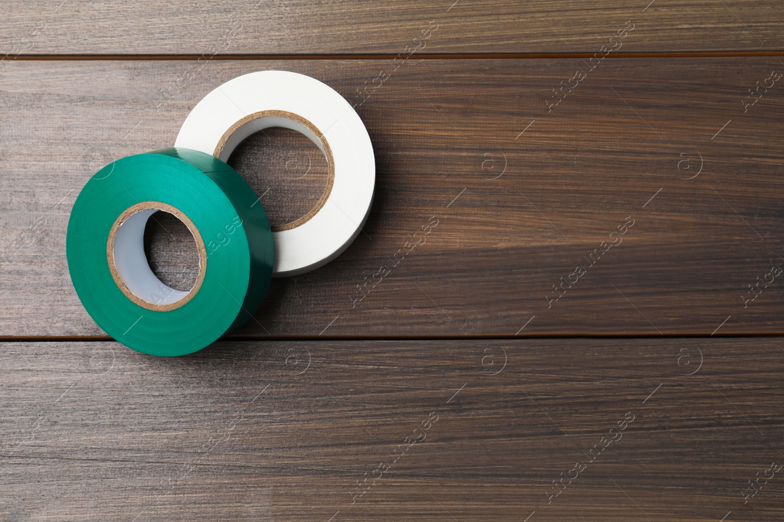 Photo of Colorful insulating tapes on wooden table, flat lay. Space for text