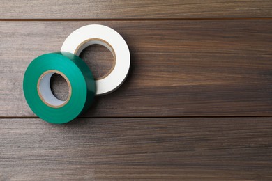 Colorful insulating tapes on wooden table, flat lay. Space for text