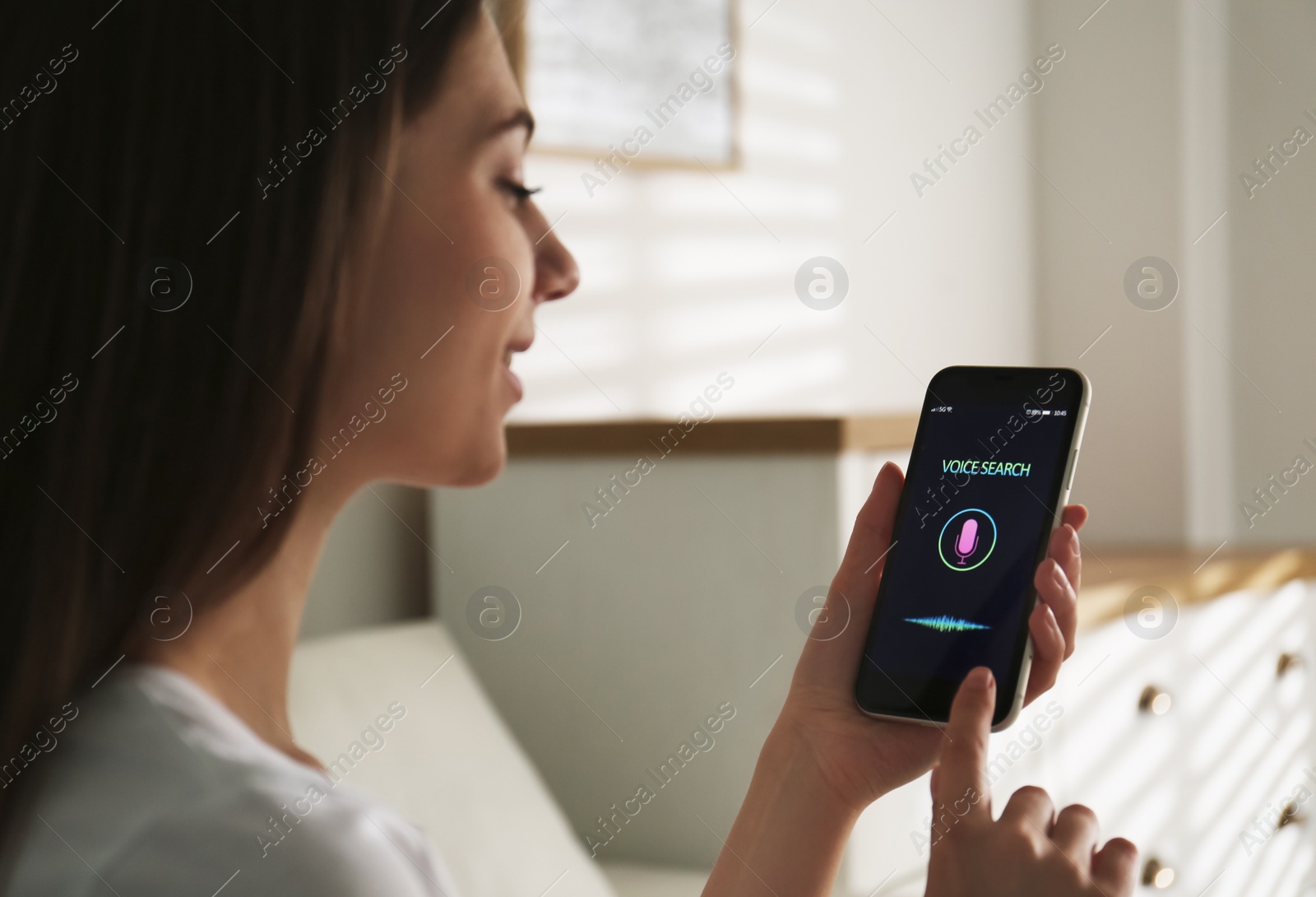 Photo of Woman using voice search on smartphone indoors