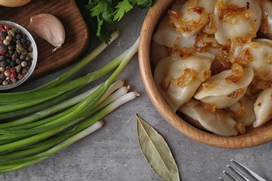 Photo of Delicious cooked dumplings with fried onion on grey table, flat lay