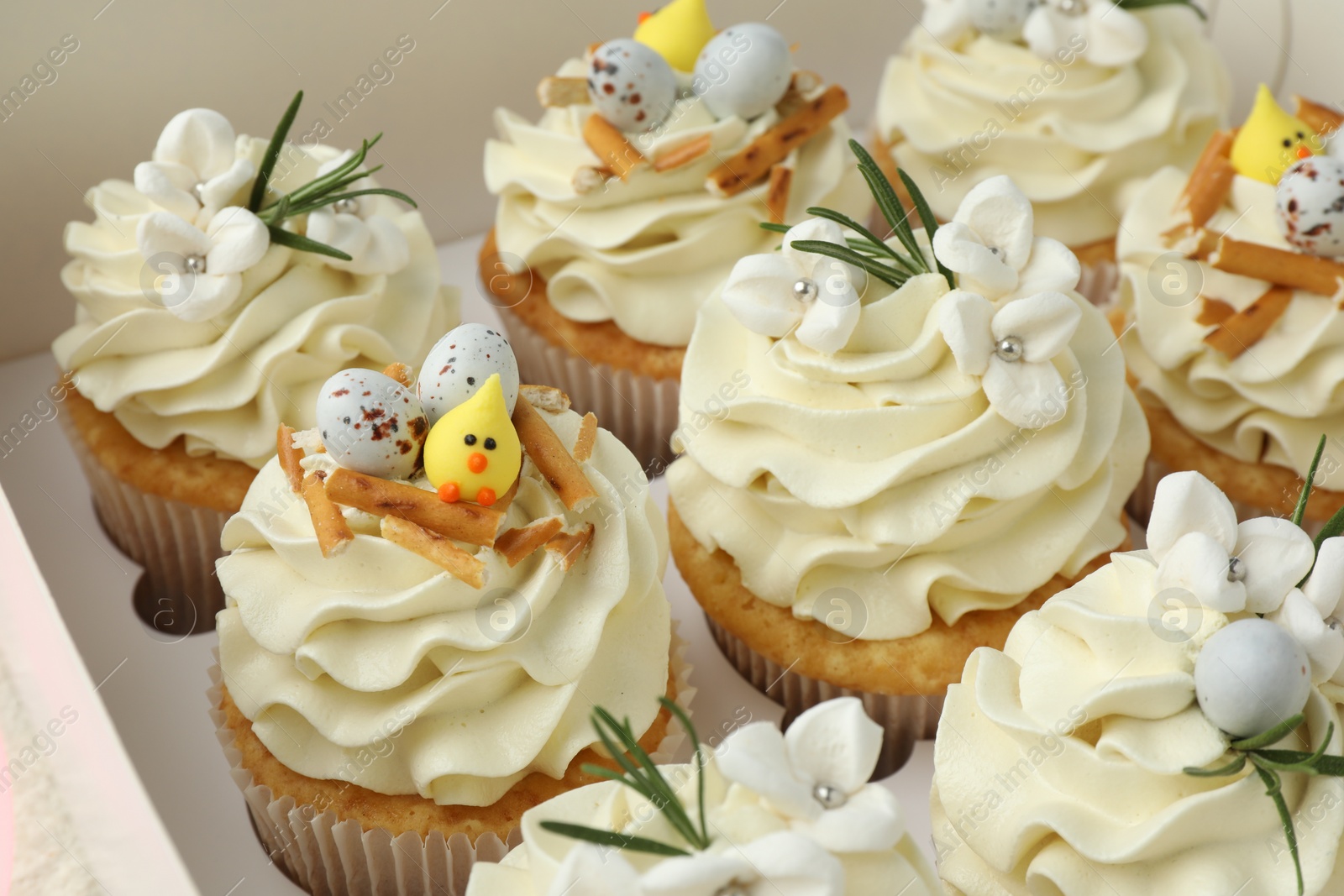 Photo of Tasty Easter cupcakes with vanilla cream in box, closeup