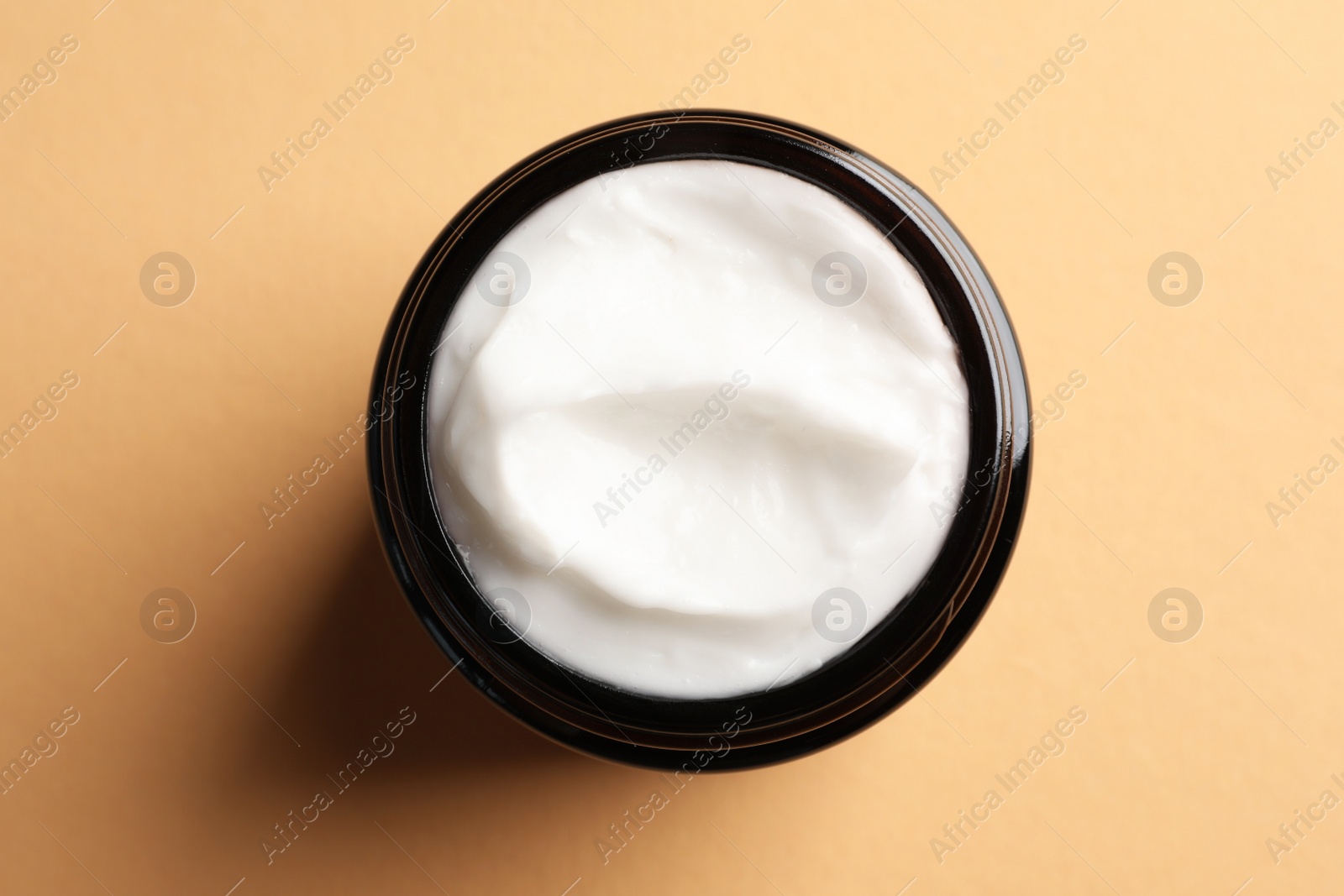 Photo of Jar of face cream on light orange background, top view