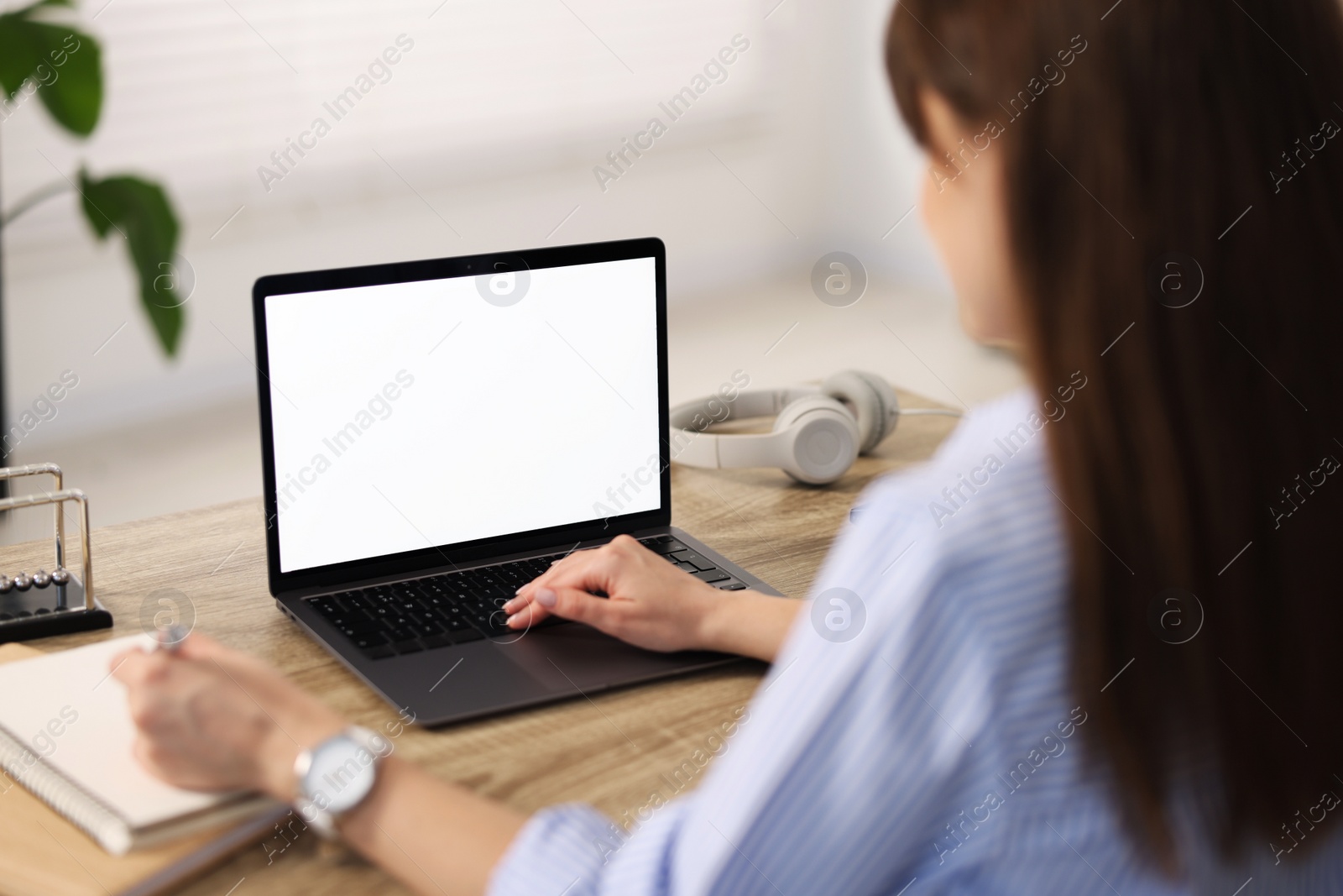 Photo of Woman taking notes during webinar at wooden table in office, selective focus