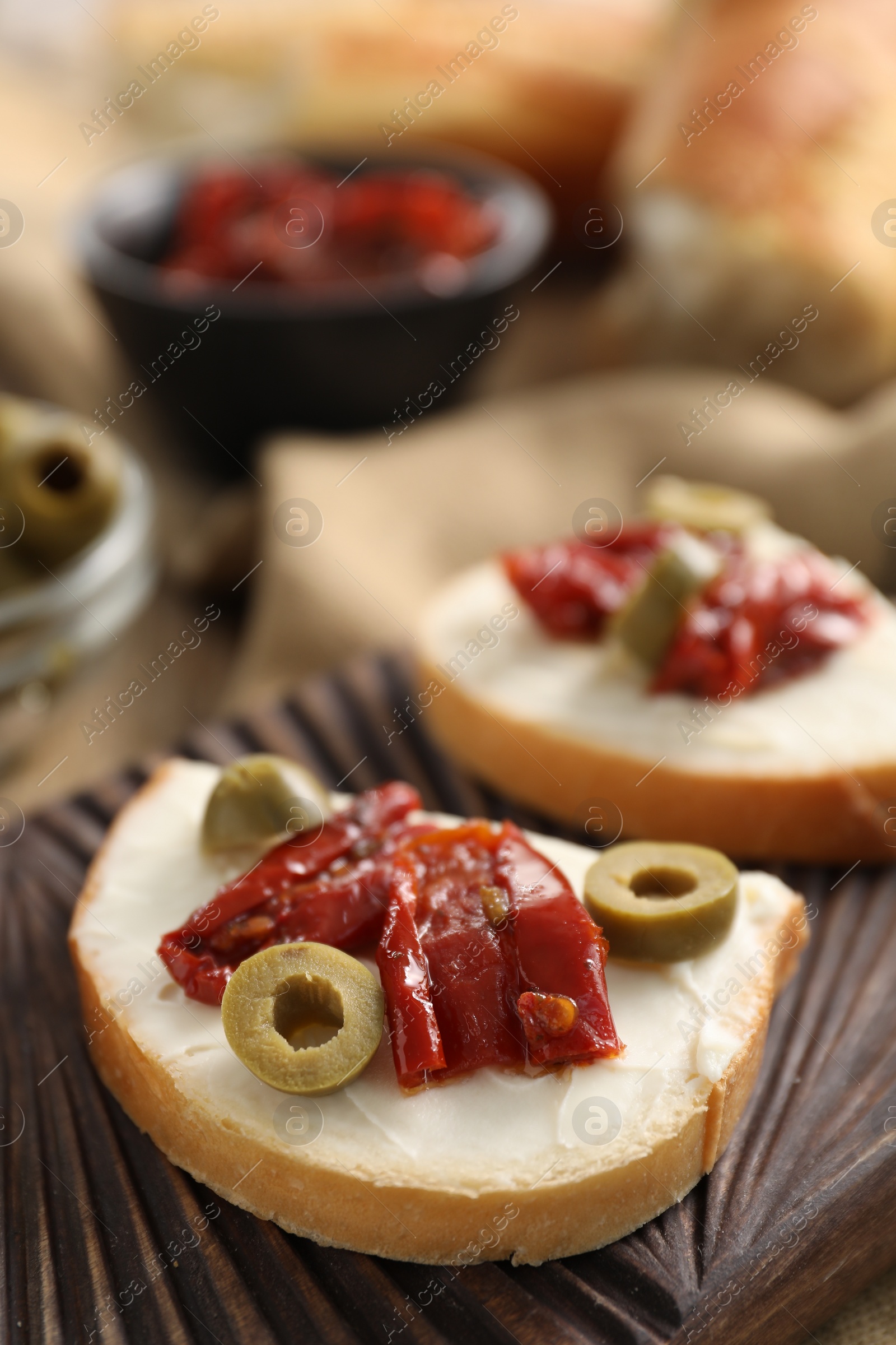 Photo of Delicious bruschettas with ricotta cheese, sun dried tomatoes and olives on table, closeup