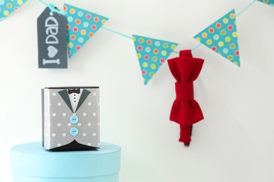 Gift box on table and bow tie hanging on garland. Father's day celebration