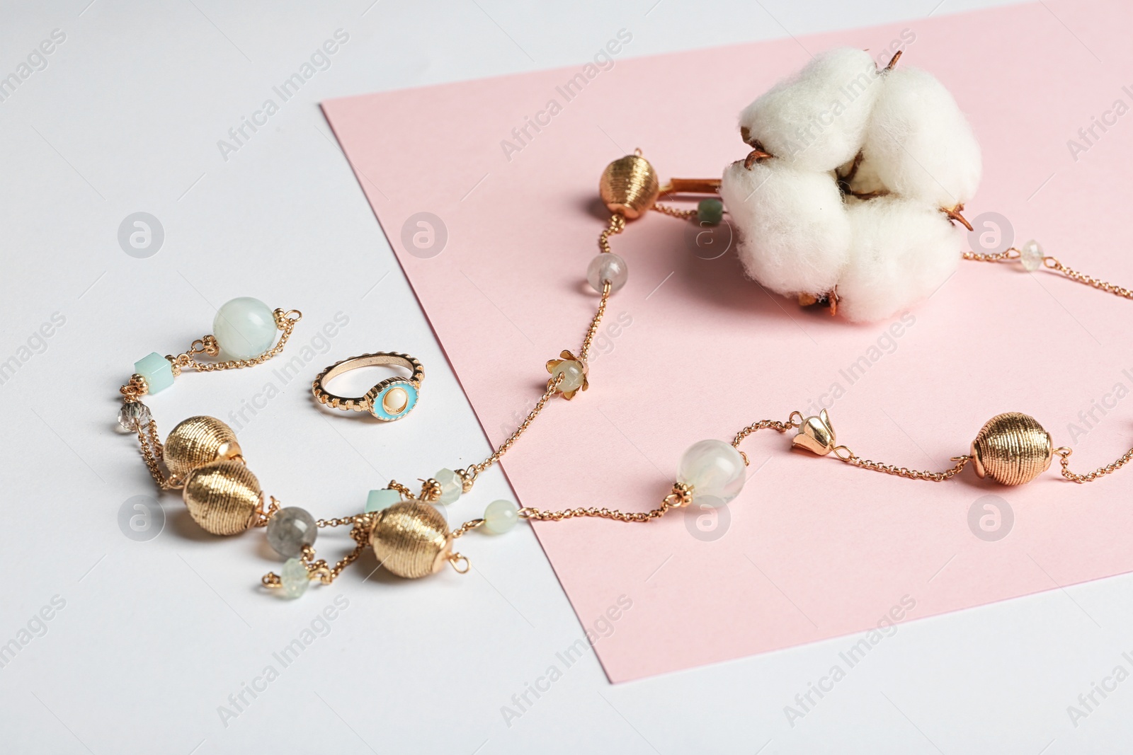 Photo of Elegant jewelry and cotton flower on color background