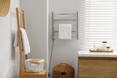 Photo of Heated rail with towel on white wall in bathroom