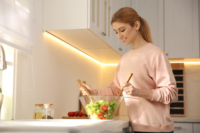 Young woman cooking salad at counter in kitchen