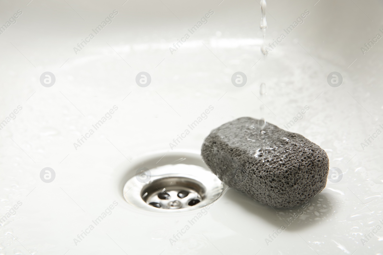 Photo of Pouring water onto pumice stone in sink, space for text