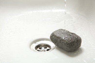 Pouring water onto pumice stone in sink, space for text