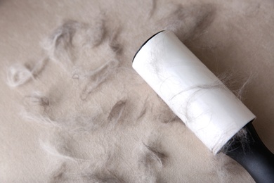 Modern lint roller and cat hair on light fabric, closeup