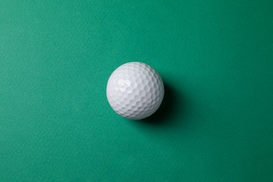 Photo of One golf ball on green background, top view