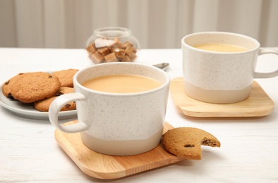 Photo of Cups with black tea and milk on table