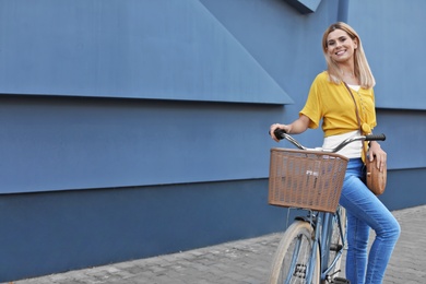 Photo of Woman with bicycle on street near gray wall