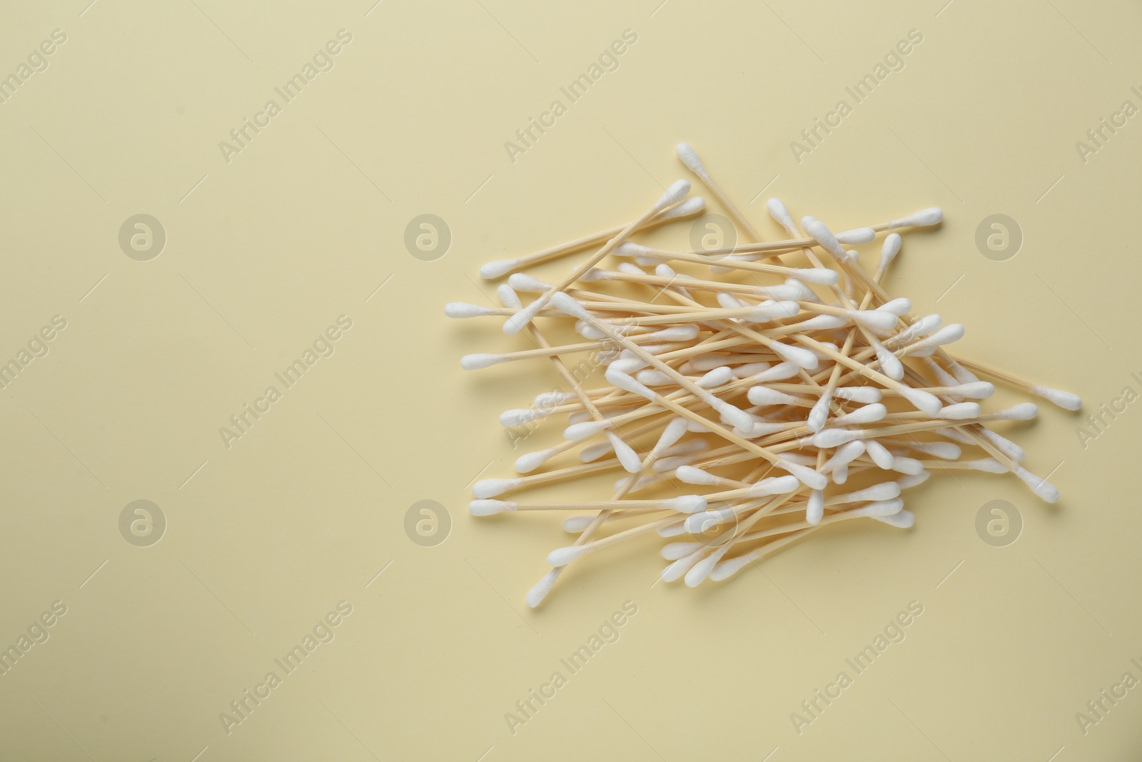 Photo of Heap of wooden cotton buds on beige background, flat lay. Space for text