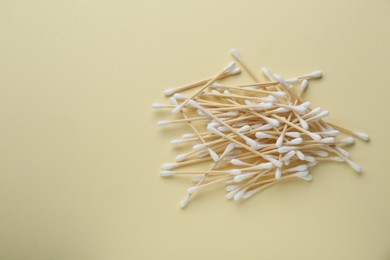 Heap of wooden cotton buds on beige background, flat lay. Space for text