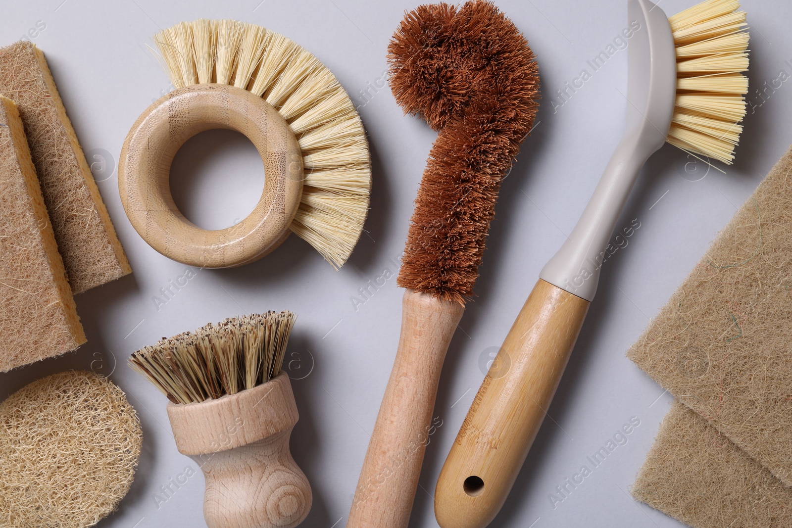 Photo of Cleaning brushes and sponges on grey background, flat lay