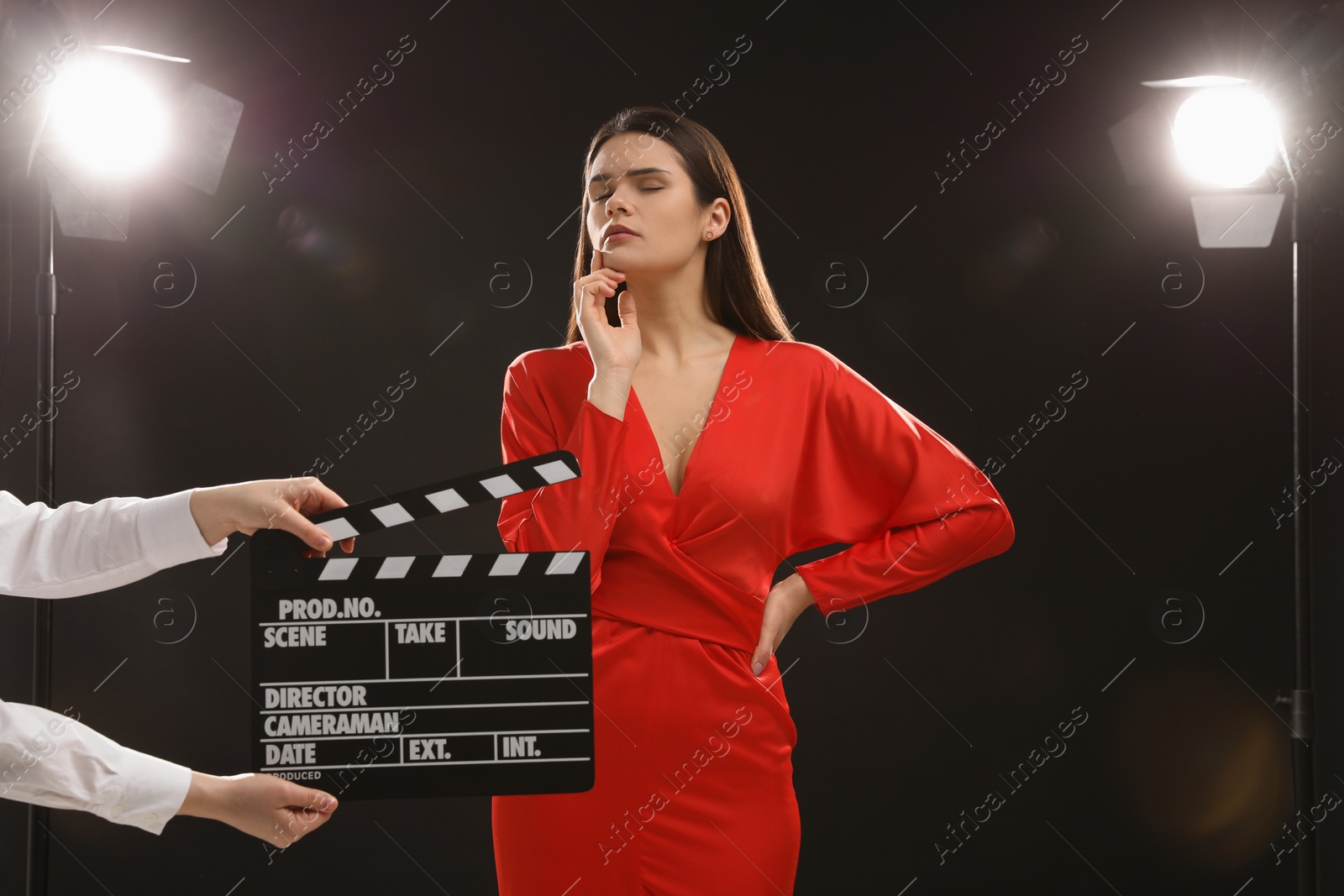 Photo of Emotional actress performing while second assistant camera holding clapperboard on stage. Film industry